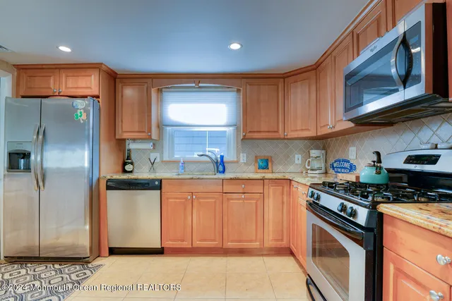 a kitchen with stainless steel appliances granite countertop a stove a sink dishwasher and a refrigerator with wooden cabinets
