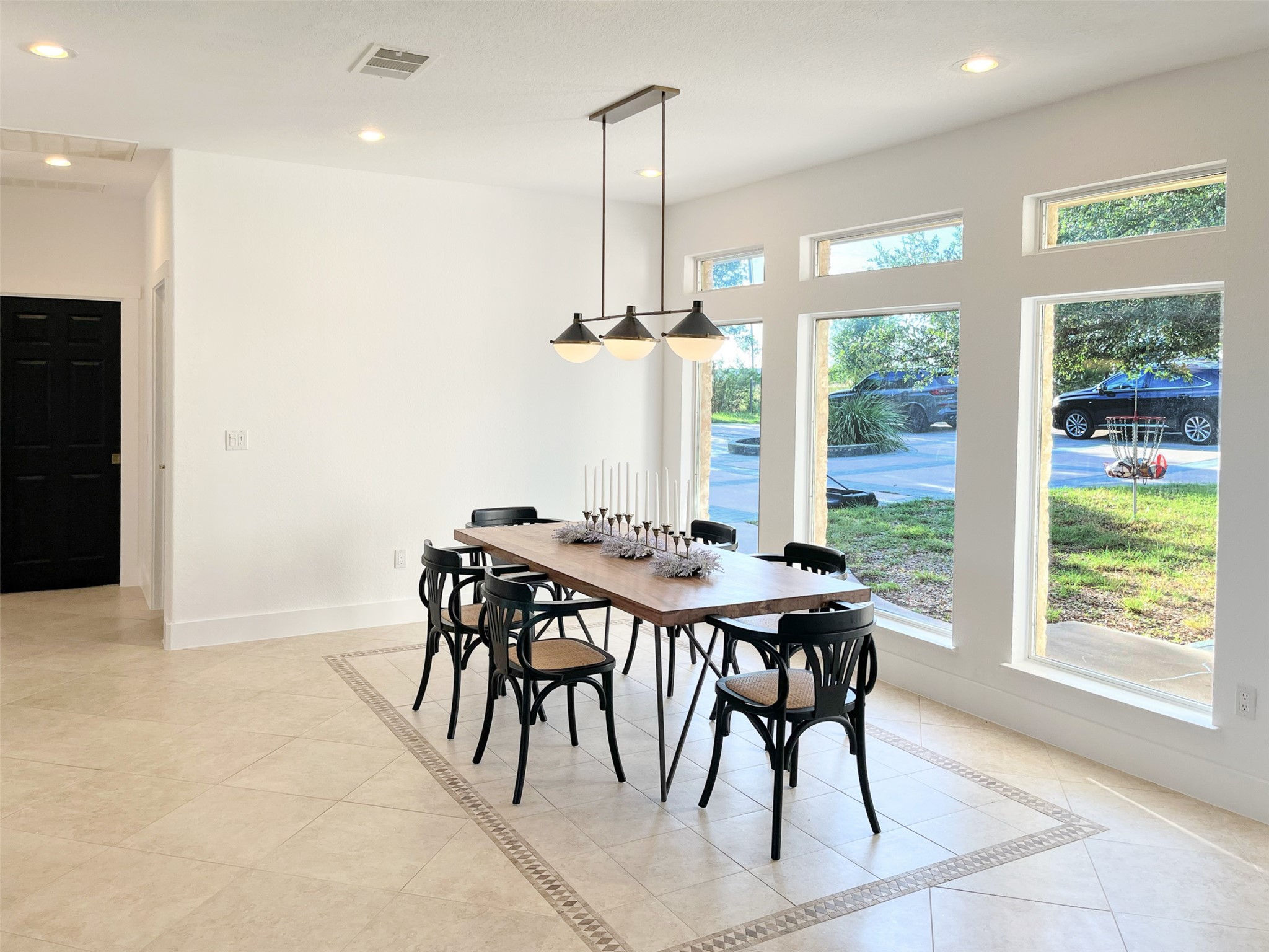 1015 Westland Ridge Road Dripping Springs, TX 78620 - Photo 8 of 32 Tall windows fill the dining space with natural light, illuminating the elegant tile flooring.