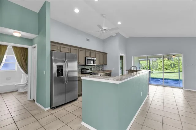 a large kitchen with stainless steel appliances granite countertop a large counter top a refrigerator and a sink