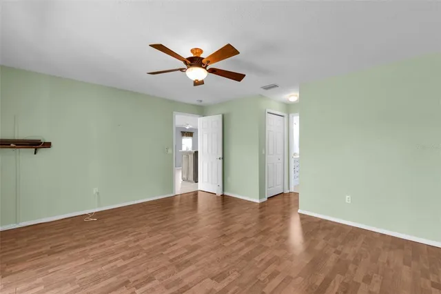 an empty room with wooden floor closet and fan