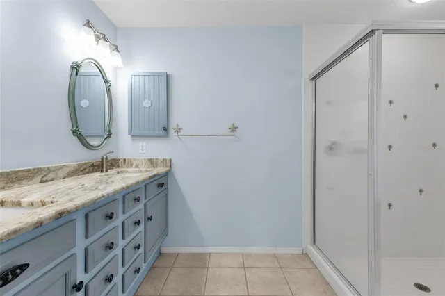 a bathroom with a granite countertop sink a mirror and shower