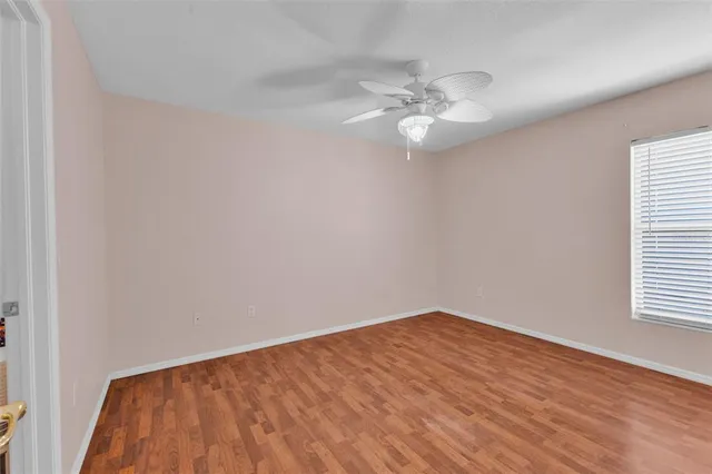 an empty room with wooden floor fan and windows
