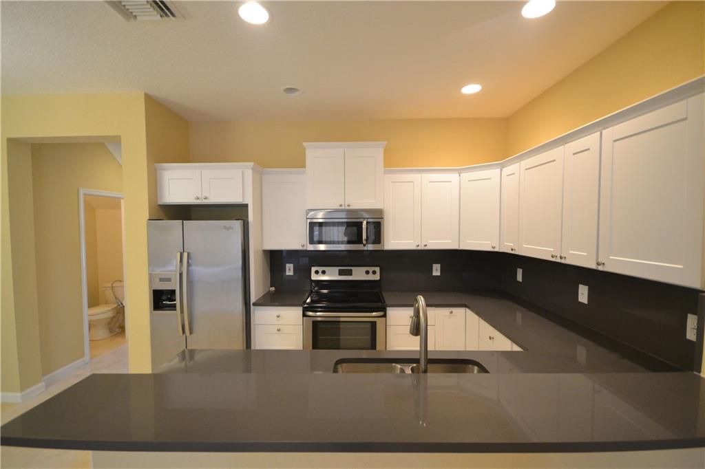 2809 Frederick Boulevard Delray Beach, FL 33483 - Photo 2 of 18 a kitchen with stainless steel appliances a stove a refrigerator and a sink