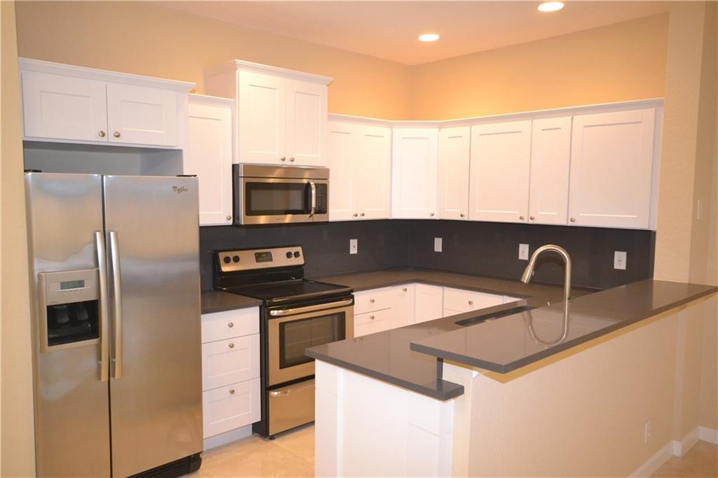 2809 Frederick Boulevard Delray Beach, FL 33483 - Photo 3 of 18 a kitchen with stainless steel appliances granite countertop a sink a stove a refrigerator a counter space and cabinets
