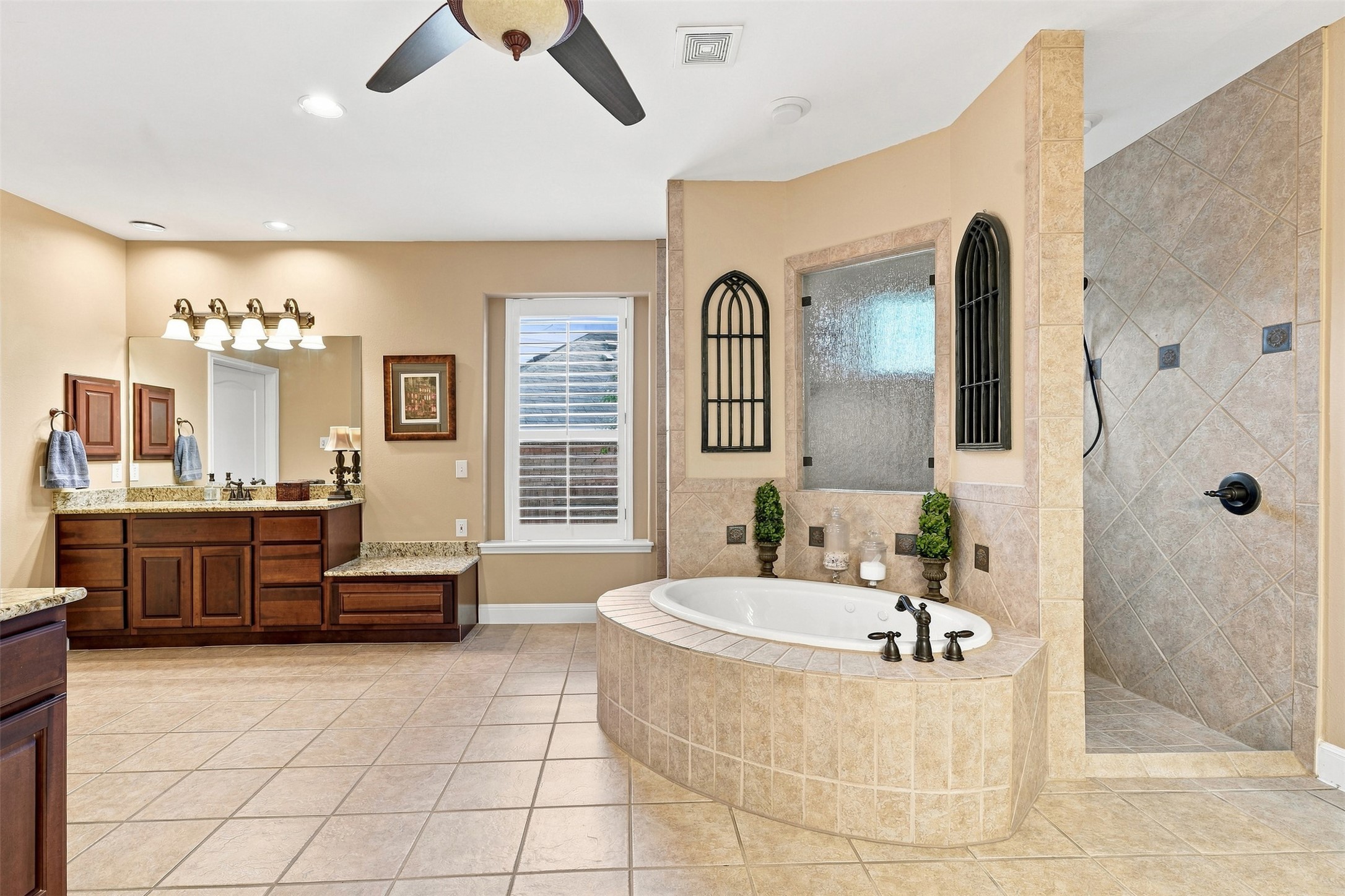 402 Ridgetop Bend Cedar Park, TX 78613 - Photo 24 of 40 A tiled bathroom features a central soaking tub and a walk-in shower alongside double vanities.