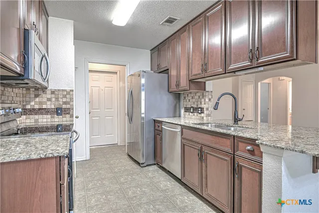 a kitchen with stainless steel appliances granite countertop a sink stove and refrigerator