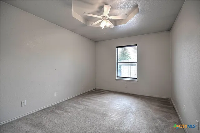 an empty room with windows and ceiling fan