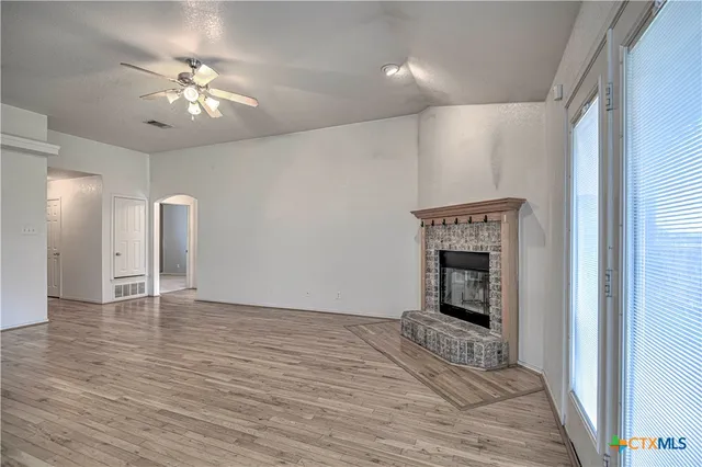 a view of an empty room with wooden floor and a fireplace