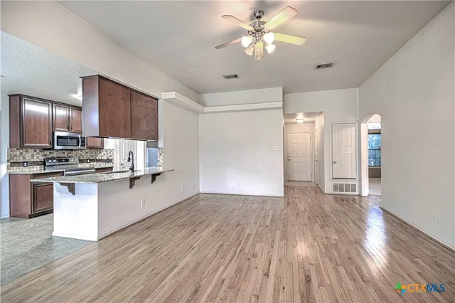 a view of kitchen with granite countertop stainless steel appliances and wooden floor