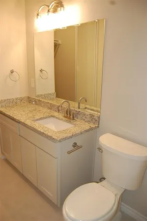 a bathroom with a granite countertop toilet sink and mirror