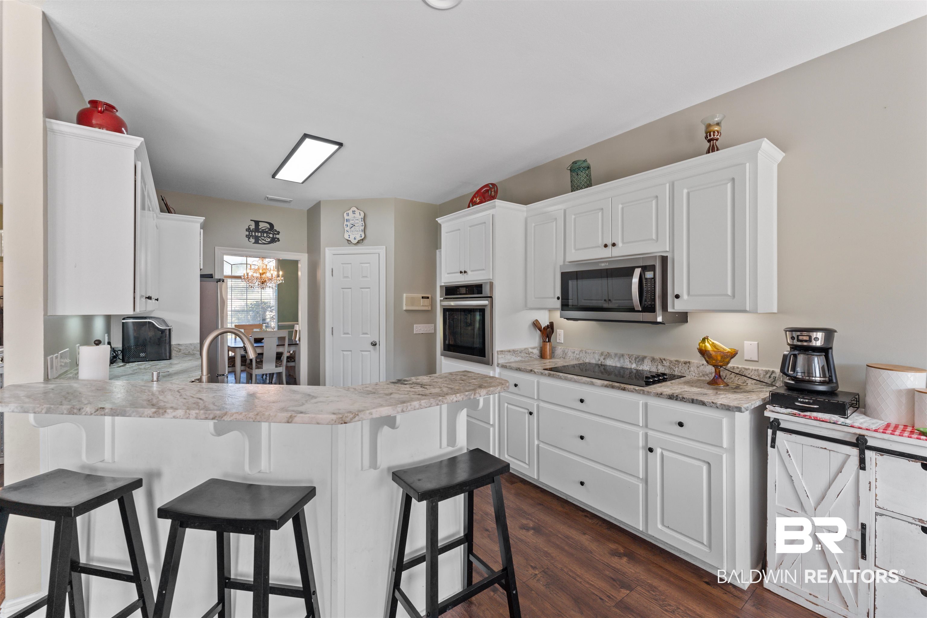 12664 Hunters Chase Foley, AL 36535 - Photo 18 of 62 Kitchen with white cabinets, a peninsula, dark wood-type flooring, and a kitchen bar