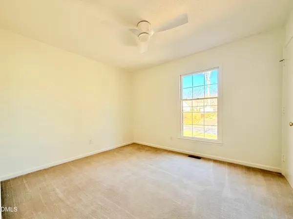 an empty room with a window and a fan