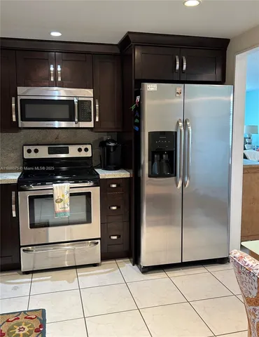 a kitchen with stainless steel appliances kitchen island granite countertop a refrigerator and a stove