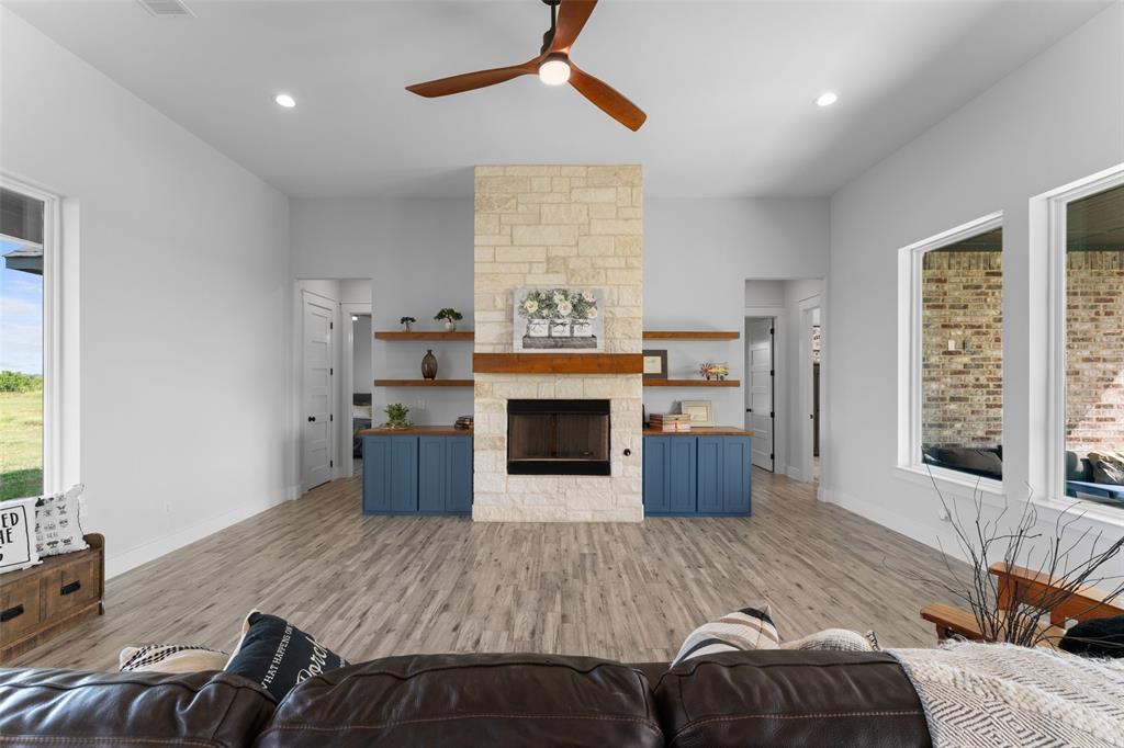 4411 Fm 751 Wills Point Wills Point, TX 75169 - Photo 10 of 40 Living area featuring a stone fireplace with a wood mantle, built-in shelving, blue cabinetry, wood-finish flooring, and recessed lighting