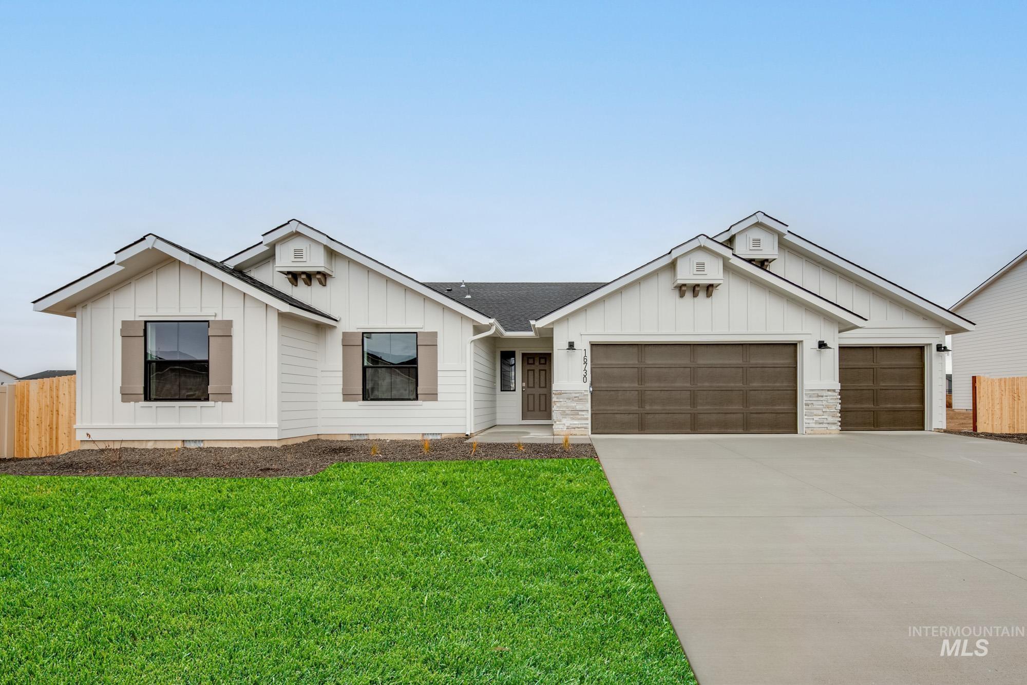 Modern farmhouse with board and batten siding, driveway, an attached garage, stone siding, and roof with shingles