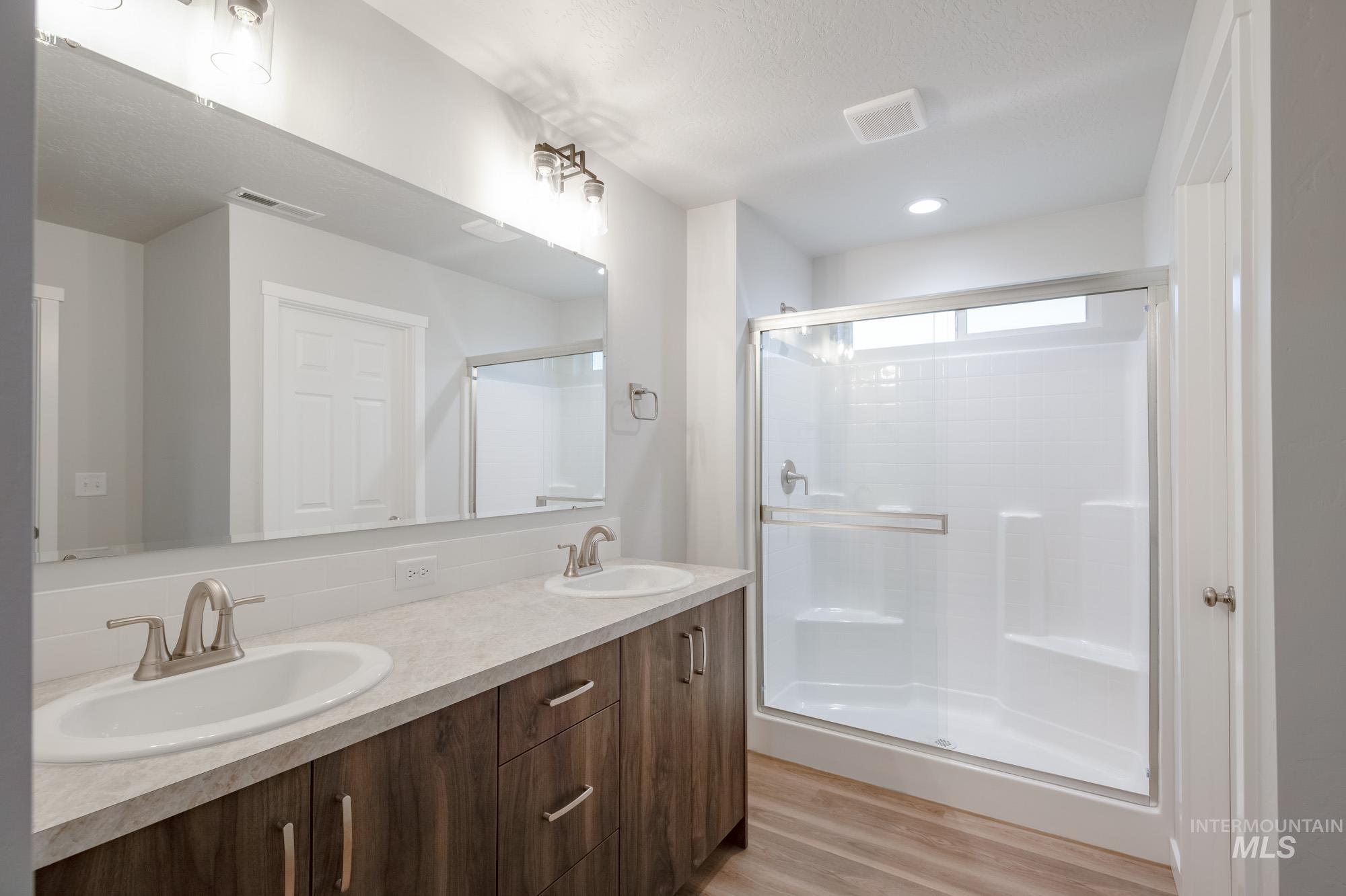 16730 Dunning Way Caldwell, ID 83607 - Photo 18 of 22 Bathroom with double vanity, light wood-style flooring, and a shower stall
