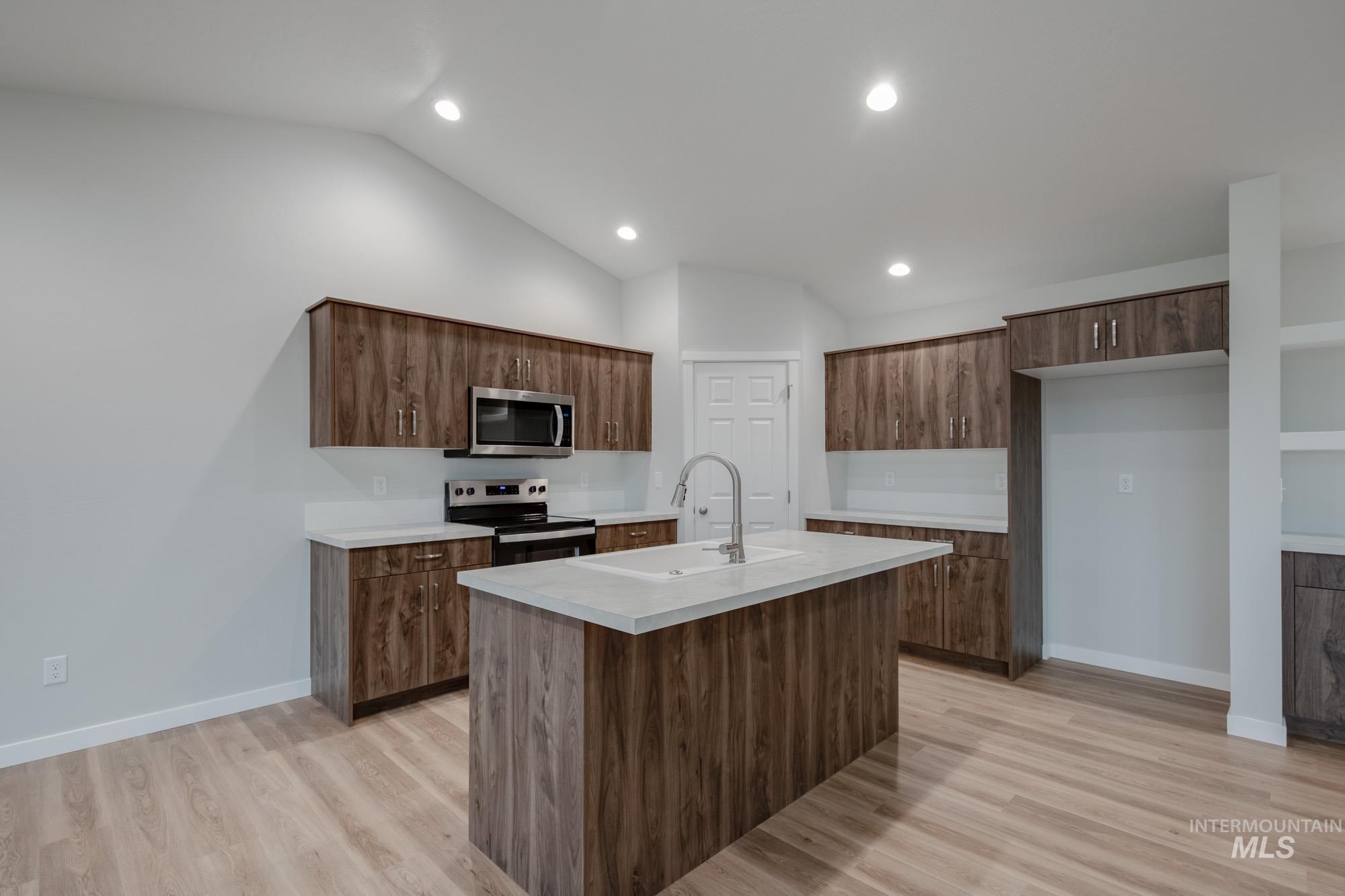 16730 Dunning Way Caldwell, ID 83607 - Photo 3 of 22 Kitchen featuring stainless steel appliances, vaulted ceiling, an island with sink, light wood-style floors, and recessed lighting