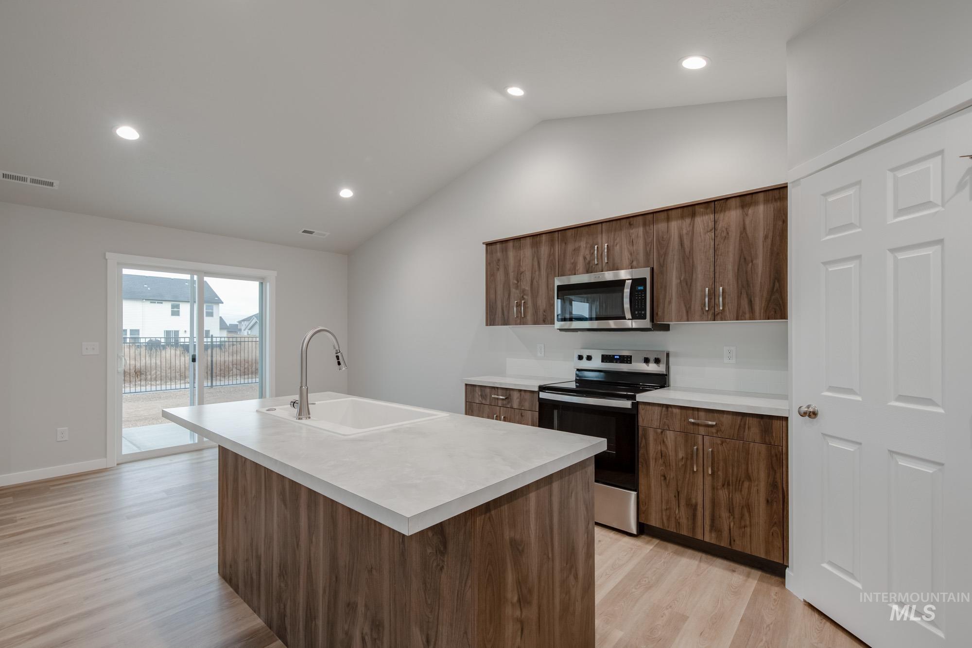 16730 Dunning Way Caldwell, ID 83607 - Photo 5 of 22 Kitchen with electric stove, light countertops, a center island with sink, vaulted ceiling, and stainless steel microwave