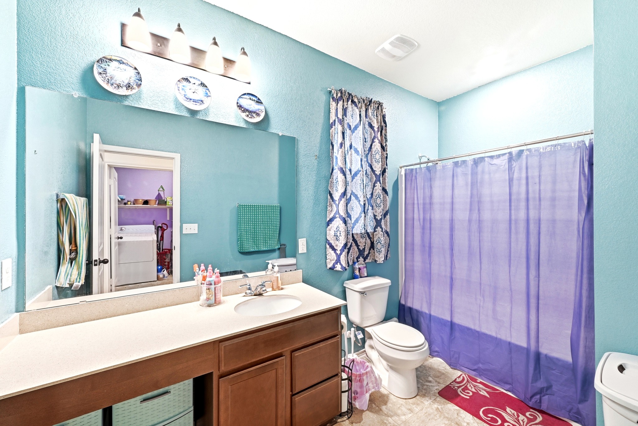 1621 Dragonfly Loop Bastrop, TX 78602 - Photo 21 of 27 Bathroom featuring a built-in vanity with a light-toned countertop, an undermount sink, and wood-finish cabinetry