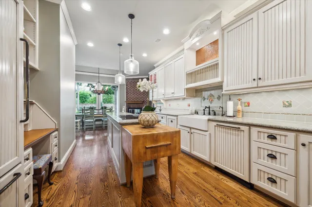 a kitchen with stainless steel appliances granite countertop a refrigerator a sink dishwasher a stove and white cabinets with wooden floor