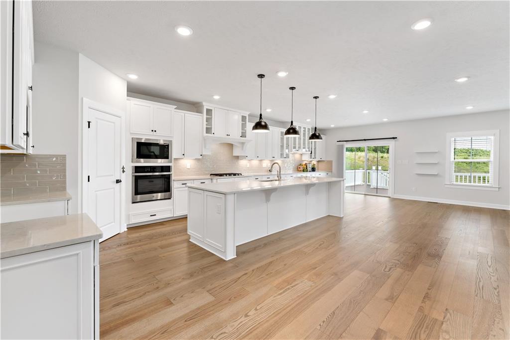 107 Abigail Drive Mars, PA 16046 - Photo 5 of 50 a large kitchen with kitchen island a stove a sink a refrigerator and white cabinets with wooden floor