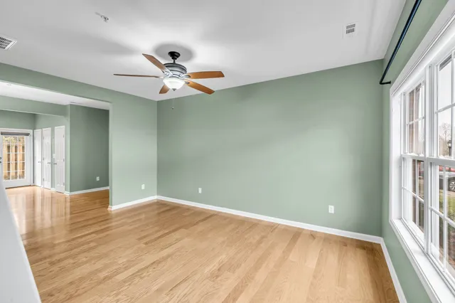a view of a big room with wooden floor and a chandelier fan