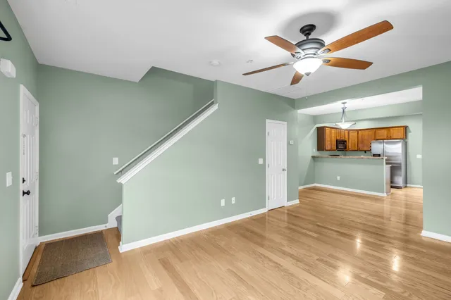 a kitchen with stainless steel appliances granite countertop a refrigerator a sink dishwasher a stove and white cabinets with wooden floor