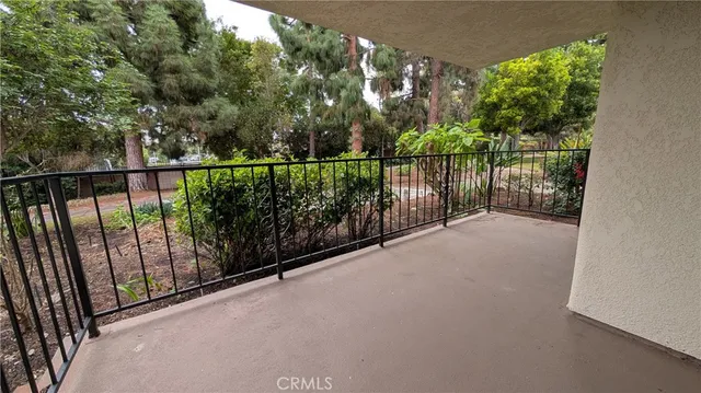 a view of an empty room with wooden floor and a kitchen