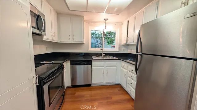 a kitchen with granite countertop white cabinets white appliances and sink