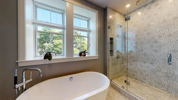a bathroom with a tub a sink and a large window