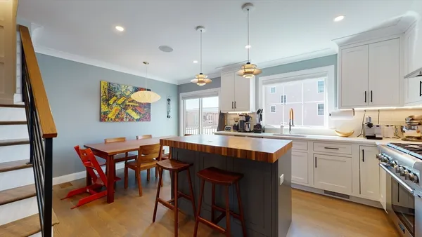 a kitchen with stainless steel appliances granite countertop a table chairs sink and cabinets