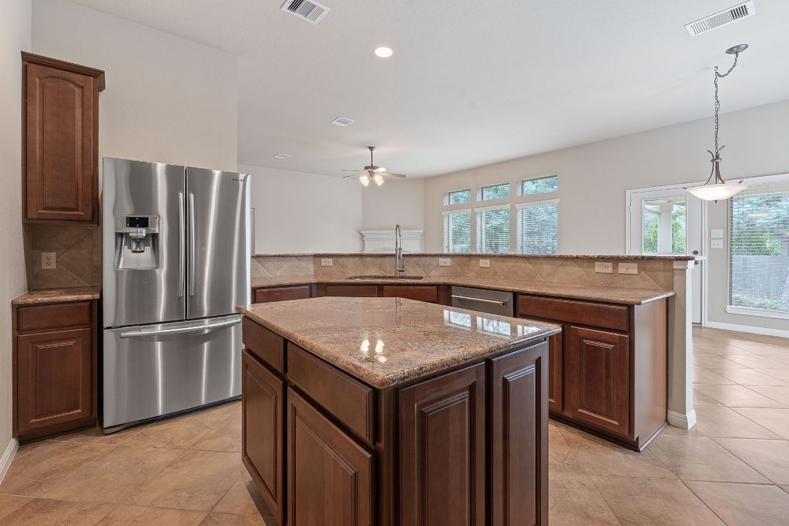 1809 Cross Draw Trail Leander, TX 78641 - Photo 5 of 22 a kitchen with stainless steel appliances granite countertop a kitchen island a stove a refrigerator and a sink