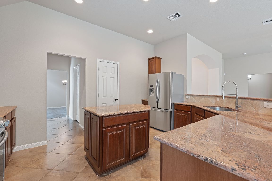 1809 Cross Draw Trail Leander, TX 78641 - Photo 6 of 22 a kitchen with stainless steel appliances granite countertop a sink and a refrigerator
