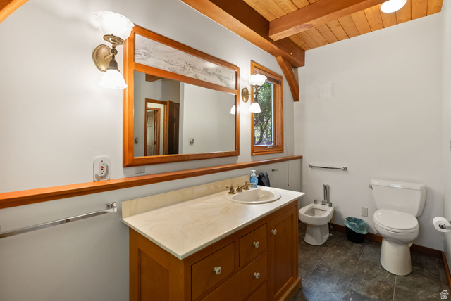 435 Canyon Road Millville, UT 84326 - Photo 21 of 113 Bathroom featuring a wood-finish vanity with an integrated sink and light-toned countertop, a large wood-framed mirror, and a window with wood trim