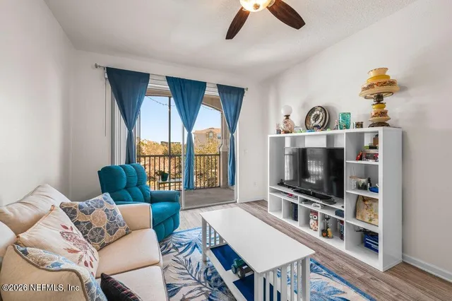 a living room with furniture a flat screen tv and a floor to ceiling window