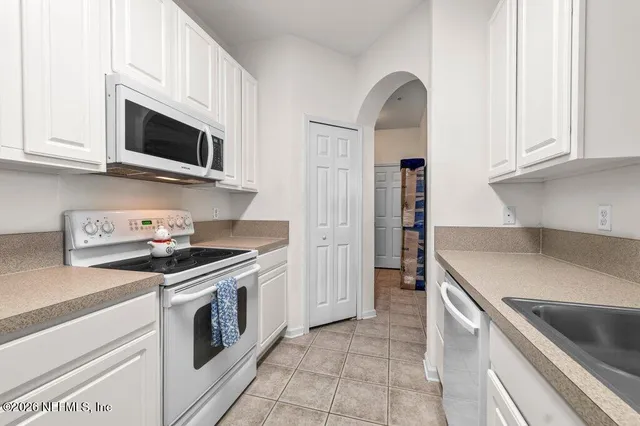 a kitchen with stainless steel appliances granite countertop a sink and a stove top oven with white countertops