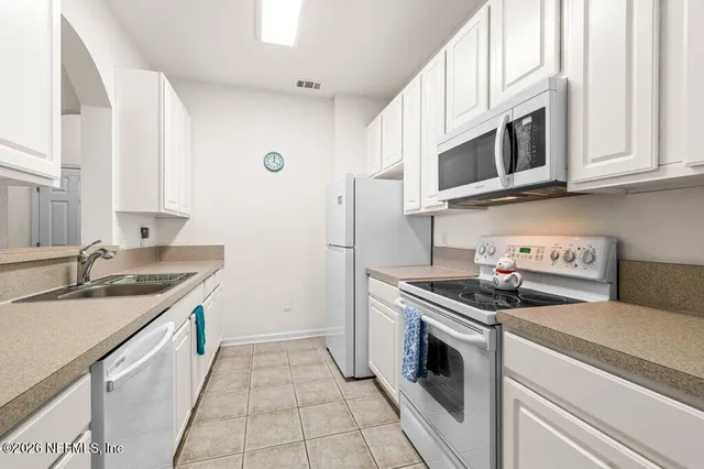 a kitchen with stainless steel appliances granite countertop white cabinets a sink and dishwasher