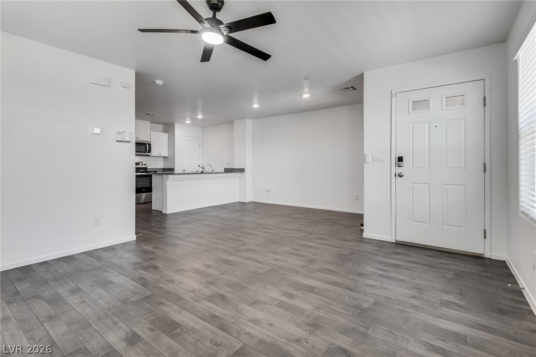 1114 Scarlet Sparrow Street Henderson, NV 89011 - Photo 25 of 25 An open floor plan seamlessly connects the kitchen and living area, featuring durable laminate flooring and a ceiling fan for comfort.