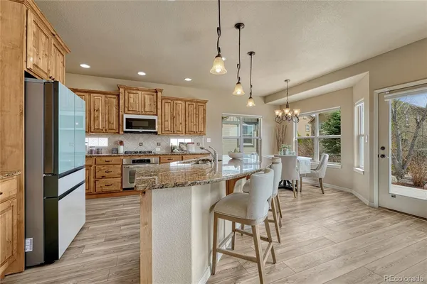 a kitchen with kitchen island granite countertop wooden floors appliances and furniture