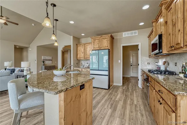 a kitchen with stainless steel appliances granite countertop a stove refrigerator a sink dishwasher with a dining table and chairs