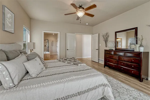 a spacious bedroom with a bed a dresser and a chandelier