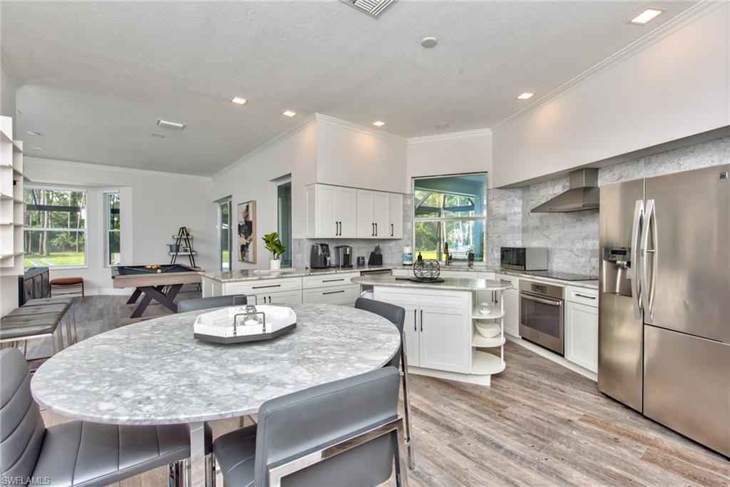 6106 Copper Leaf Lane Naples, FL 34116 - Photo 4 of 35 a kitchen with a dining table wooden cabinets and stainless steel appliances