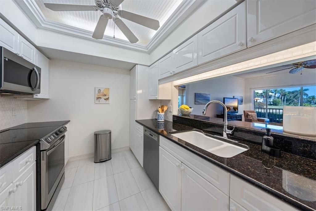 760 Willowbrook Drive, Unit 1204 Naples, FL 34108 - Photo 11 of 25 a kitchen with granite countertop a sink stainless steel appliances a counter space and cabinets
