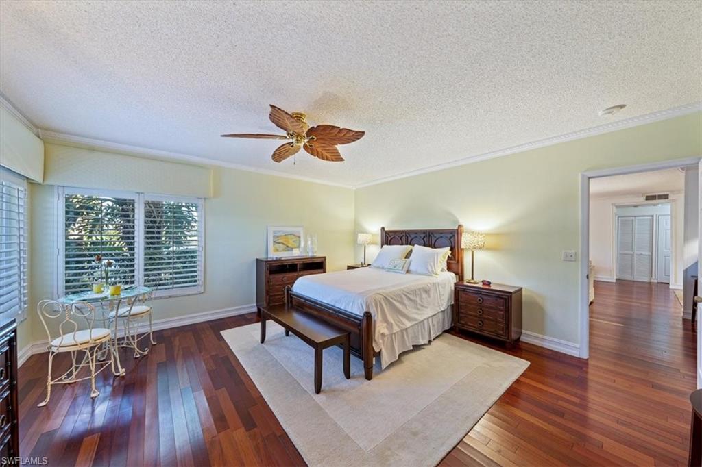 760 Willowbrook Drive, Unit 1204 Naples, FL 34108 - Photo 14 of 25 a bedroom with a bed and a table with wooden floor
