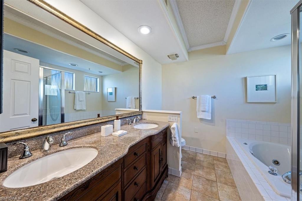 760 Willowbrook Drive, Unit 1204 Naples, FL 34108 - Photo 15 of 25 a bathroom with a granite countertop double vanity sink a mirror and a bathtub