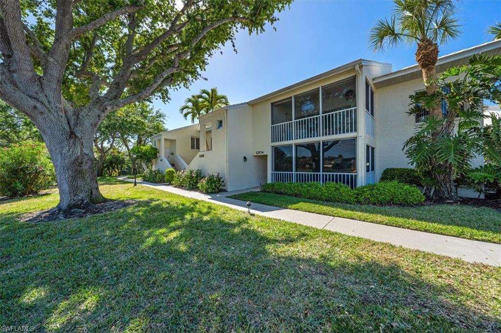 760 Willowbrook Drive, Unit 1204 Naples, FL 34108 - Photo 22 of 25 a view of a house with a yard and a large tree