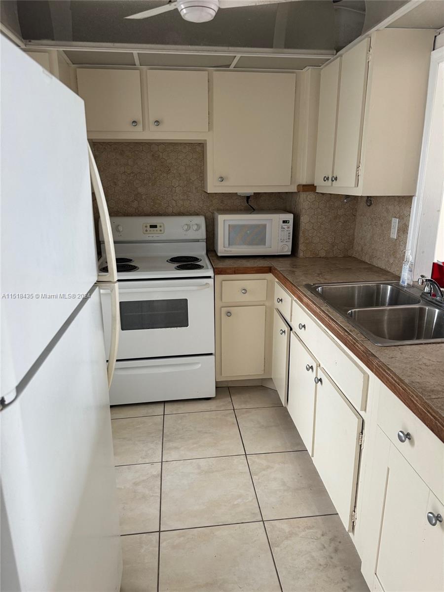 8000 Harding Avenue, Unit 4D Miami Beach, FL 33141 - Photo 4 of 16 a kitchen with cabinets a sink and appliances