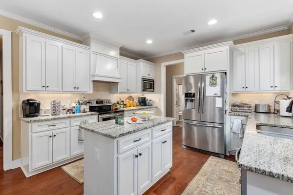 a kitchen with a stove a kitchen island white cabinets and wooden floor