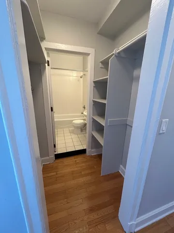 a view of walk in closet with wooden floor and staircase