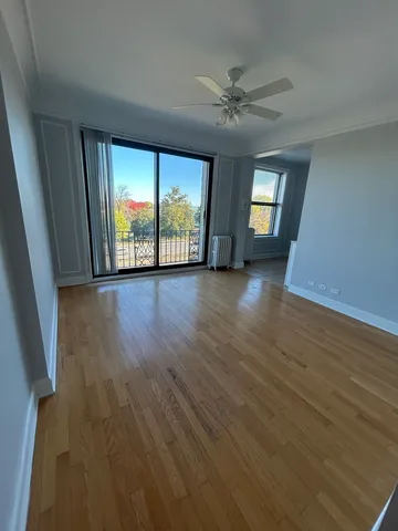 an empty room with wooden floor fan and windows